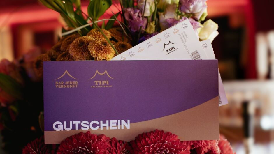 Gutscheinumschlag von BAR JEDER VERNUNFT und TIPI AM KANZLERAMT, arrangiert in einem Blumenstrauß.